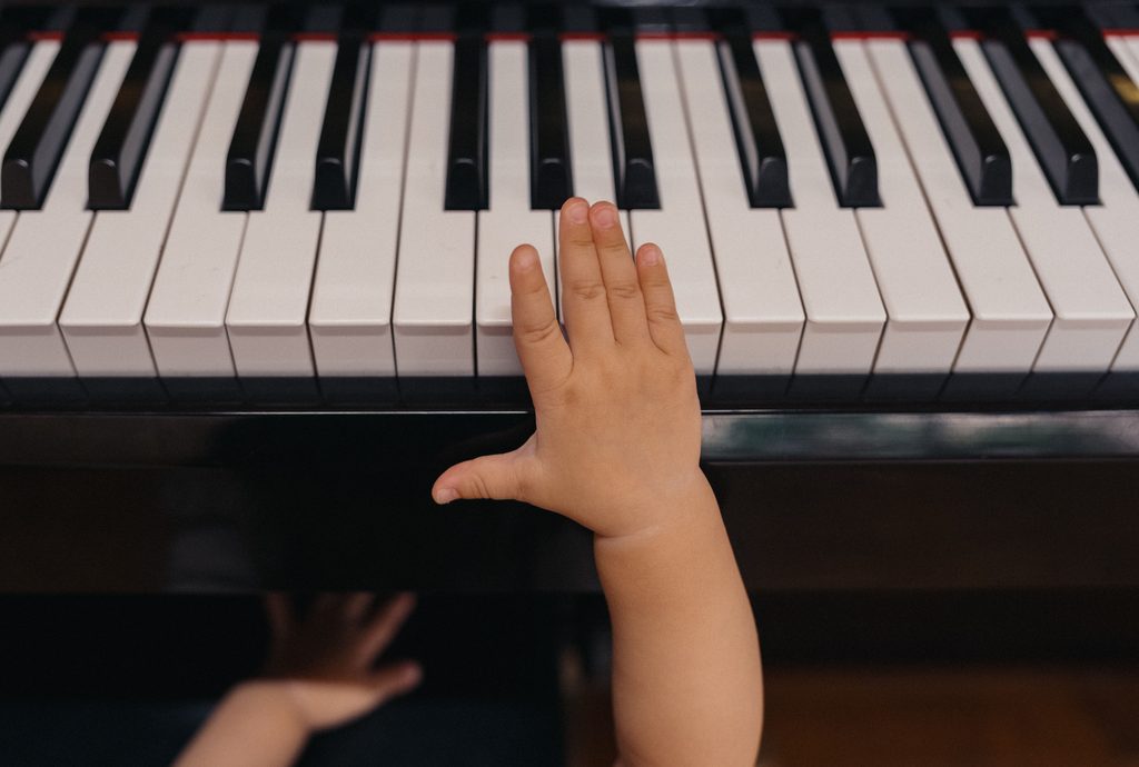 Eine Kinderhand spielt auf einer Klaviertastatur - musikalisches Lernen und Üben.